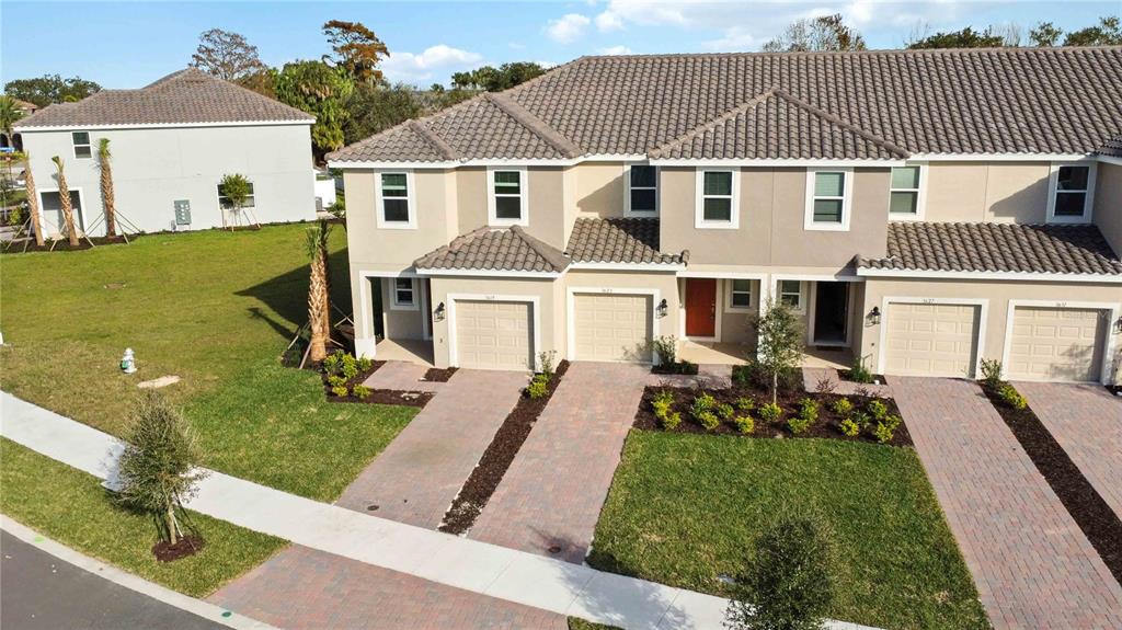 An exterior view of a multi-unit townhouse complex with beige siding and paved driveways — 3623 LANDING NET DRIVE, KISSIMMEE, FL
