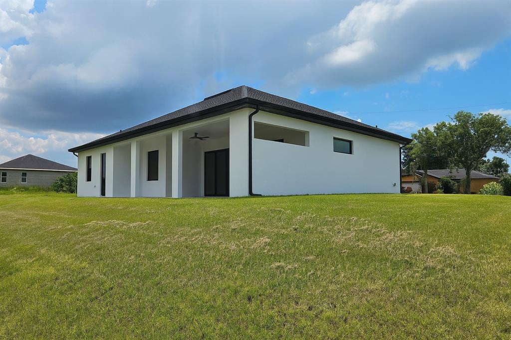 A white, modern single-story house with a covered patio sits on a large grassy lot — 1321 NE 19 TERRACE, CAPE CORAL, FL