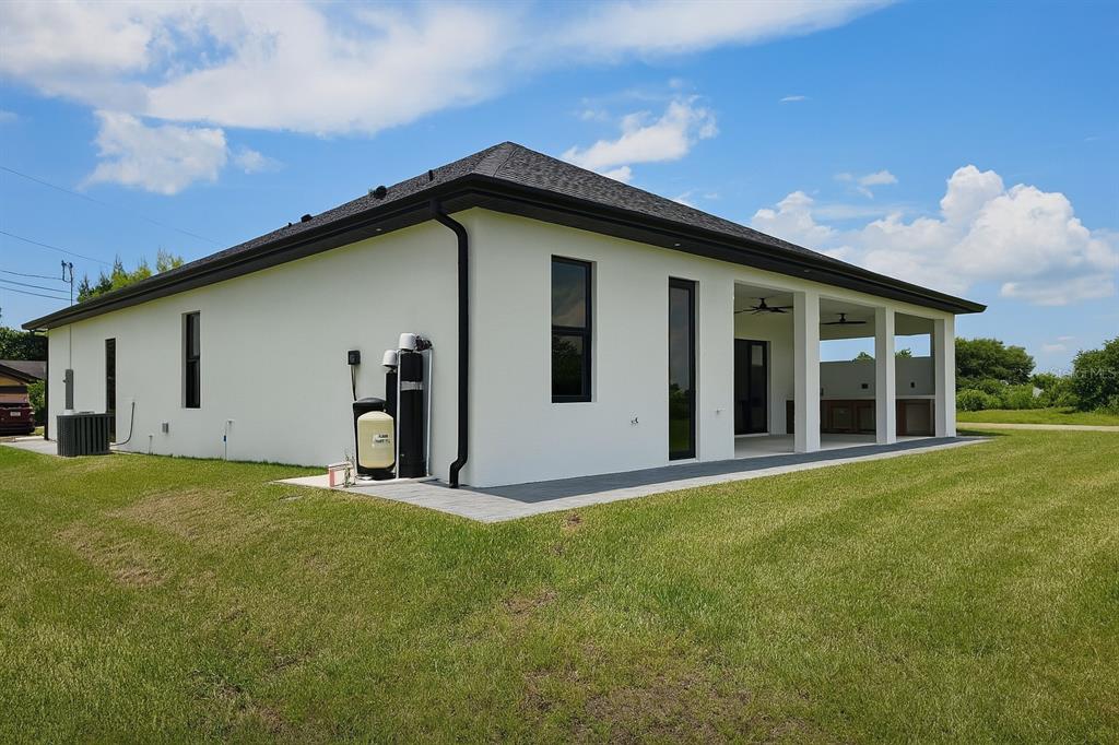 The exterior of a white modern house with a covered patio and water treatment system — 1321 NE 19 TERRACE, CAPE CORAL, FL