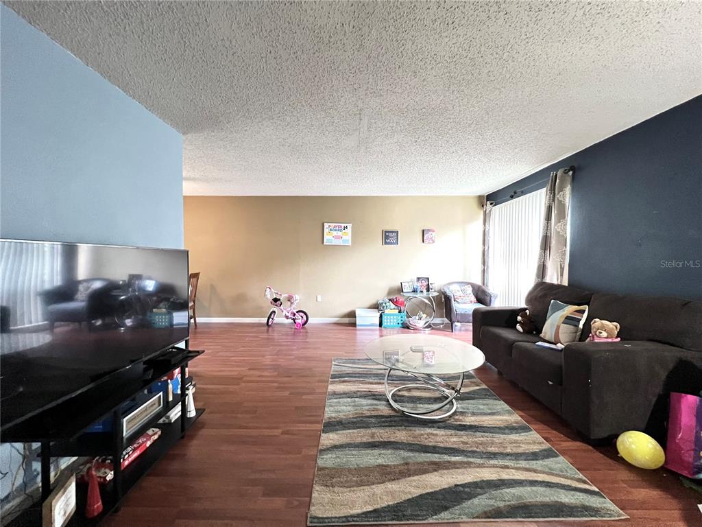A living room features wood-look flooring, a dark sofa, a glass coffee table, and a television — 2811 SW ARCHER ROAD UNIT 190, GAINESVILLE, FL