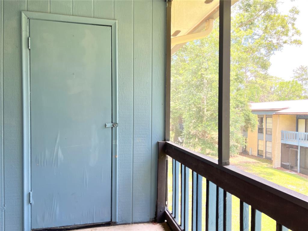 A light blue door leads to a storage closet on a screened-in balcony — 2811 SW ARCHER ROAD UNIT 190, GAINESVILLE, FL