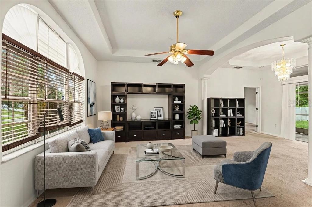 A living room features a tray ceiling, a ceiling fan, and dark wood shelving units — 2405 AINSWORTH AVENUE, SPRING HILL, FL