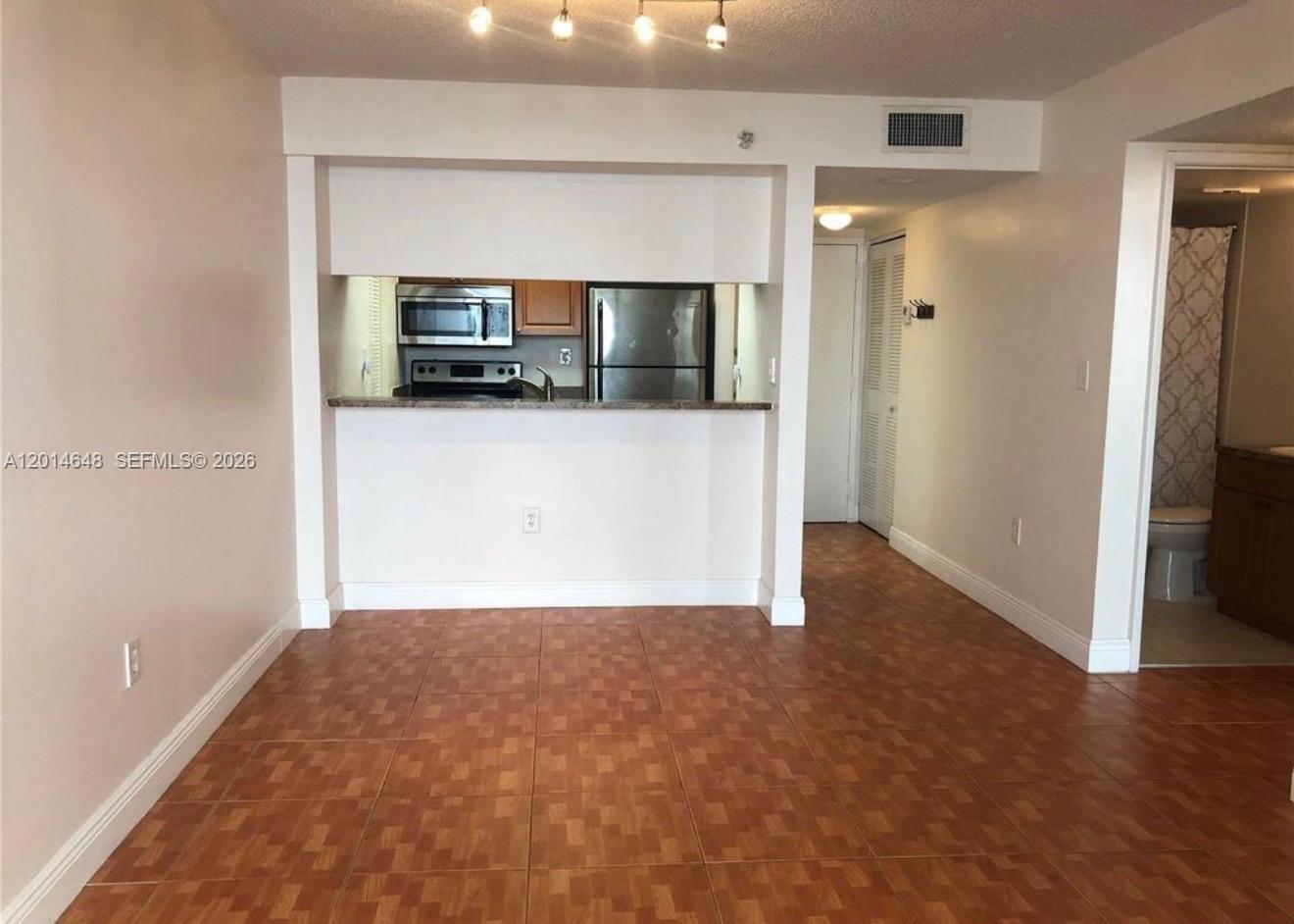 A dining area with tiled floors opens to a kitchen featuring stainless steel appliances — 800 N Miami Ave # 407, Miami FL 33136, MIAMI, FL