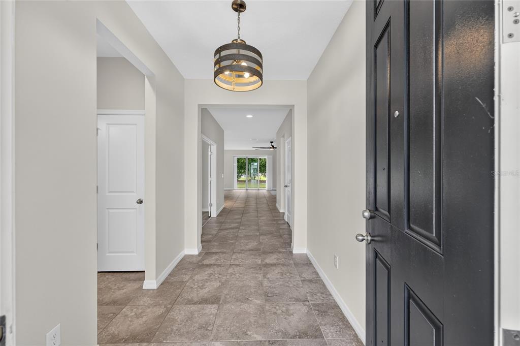 An entryway with tile flooring leads to a hallway with a view of the backyard — 5601 SW 50TH AVENUE, OCALA, FL