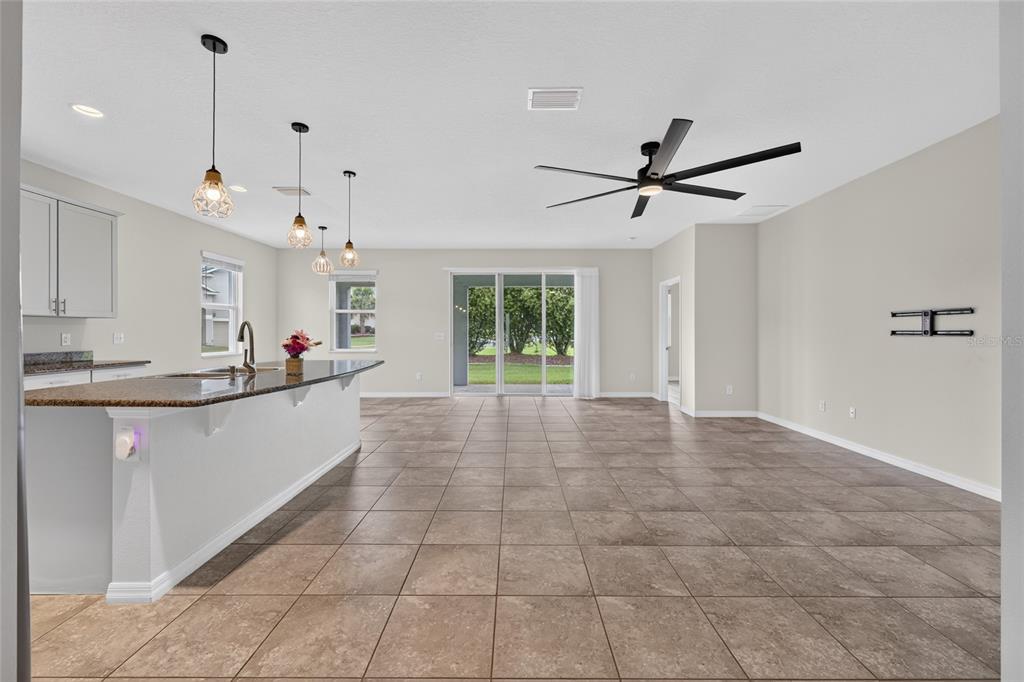 An open-concept kitchen and living area features tile flooring, a granite island, and sliding doors — 5601 SW 50TH AVENUE, OCALA, FL