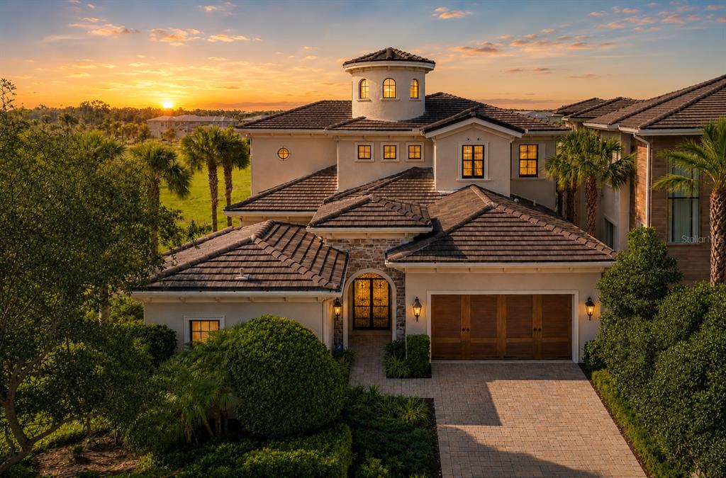 An exterior view of a two-story Mediterranean-style house with a tile roof at sunset — 340 MUIRFIELD LOOP, REUNION, FL
