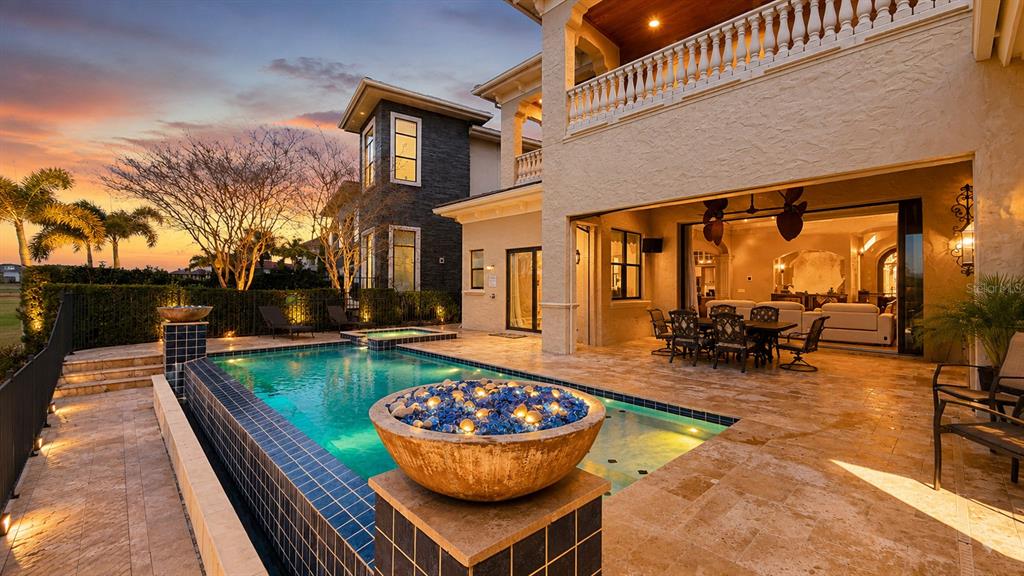 A luxury home patio features a swimming pool, a fire bowl, and an outdoor dining area — 340 MUIRFIELD LOOP, REUNION, FL