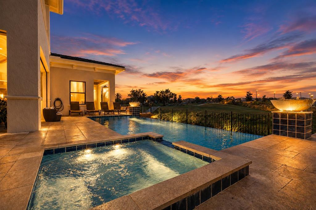 An infinity pool and hot tub overlook a golf course at sunset — 340 MUIRFIELD LOOP, REUNION, FL