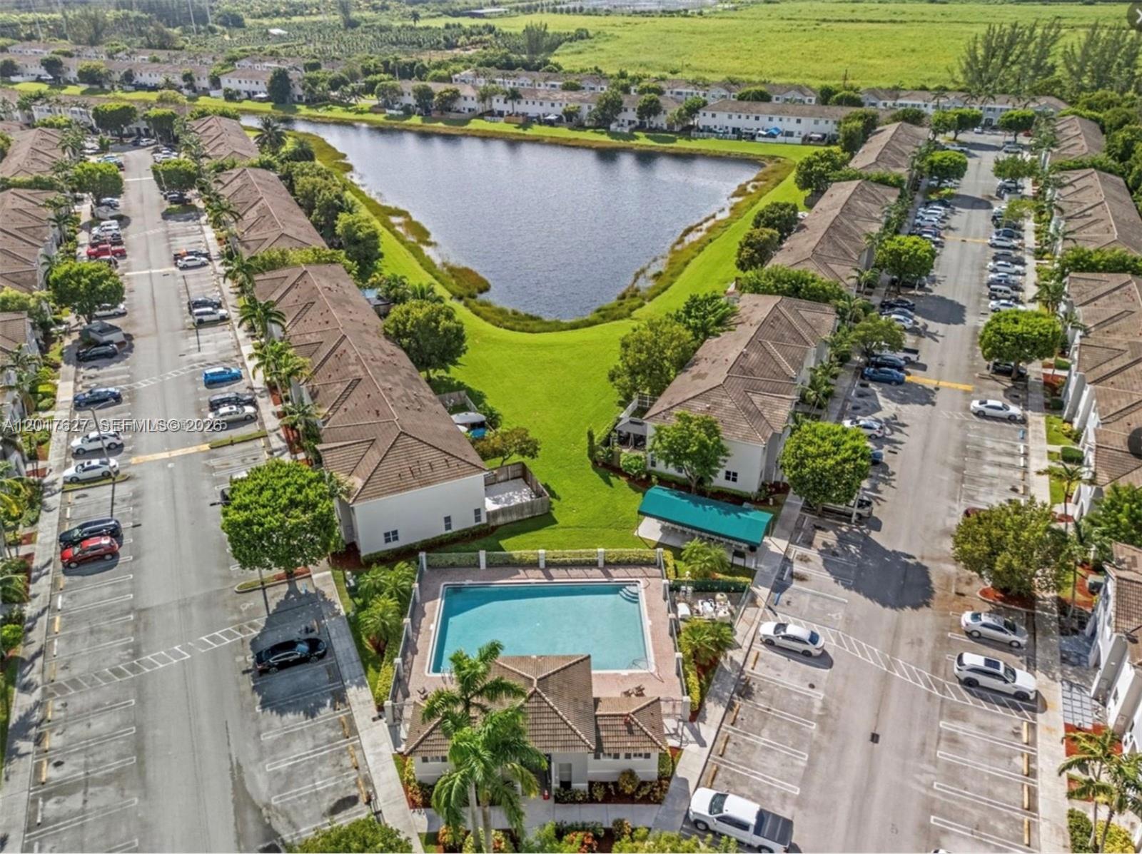 An aerial view shows a residential complex with a swimming pool, lake, and parking lots — 2953 SE 15th Ter, Homestead FL 33035, HOMESTEAD, FL