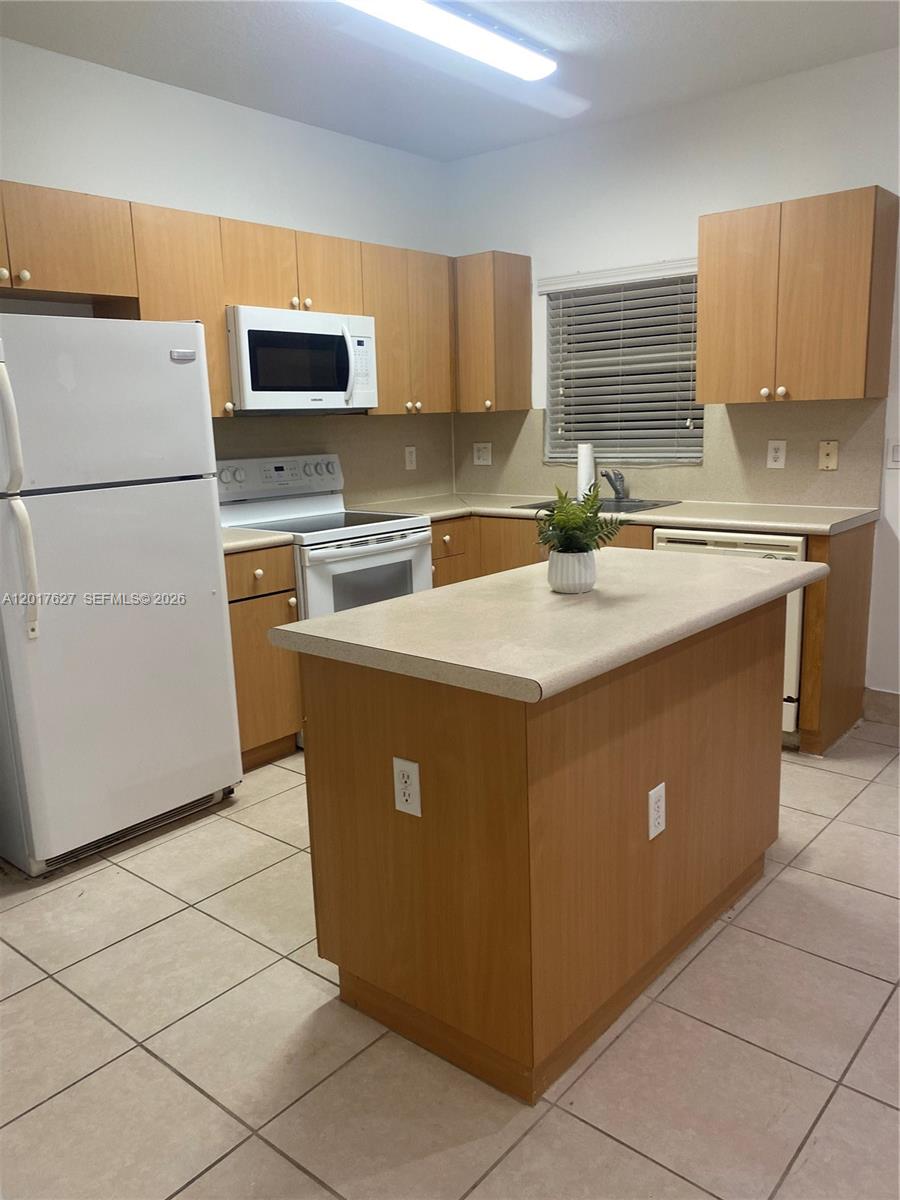 A kitchen features light wood cabinets, a white refrigerator, and a central island — 2953 SE 15th Ter, Homestead FL 33035, HOMESTEAD, FL