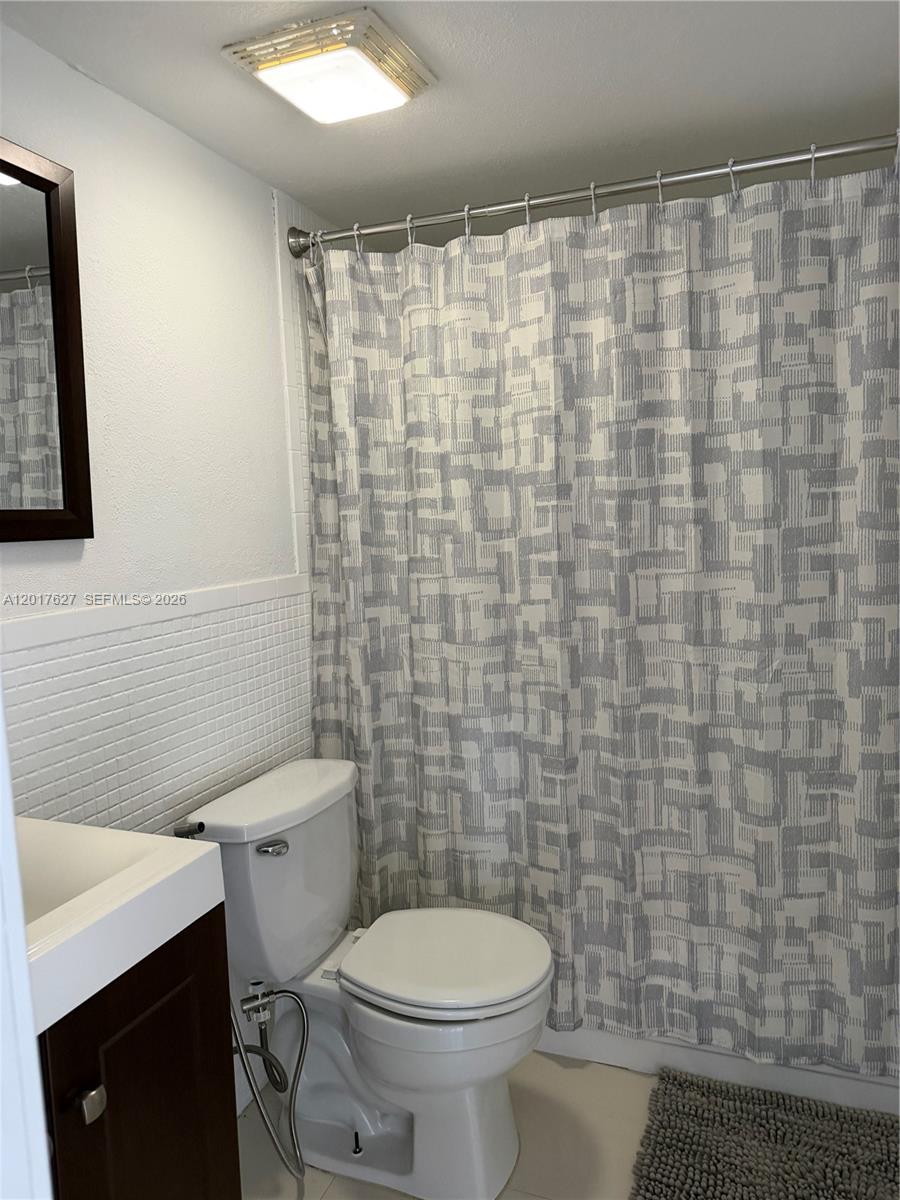 A bathroom features a white toilet, a dark wood vanity, and a patterned shower curtain — 2953 SE 15th Ter, Homestead FL 33035, HOMESTEAD, FL