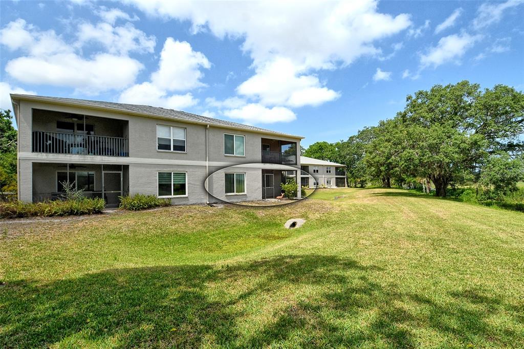 The exterior of a two-story apartment building features a grassy lawn and a screened patio — 383 BOBBY JONES ROAD UNIT 383, SARASOTA, FL