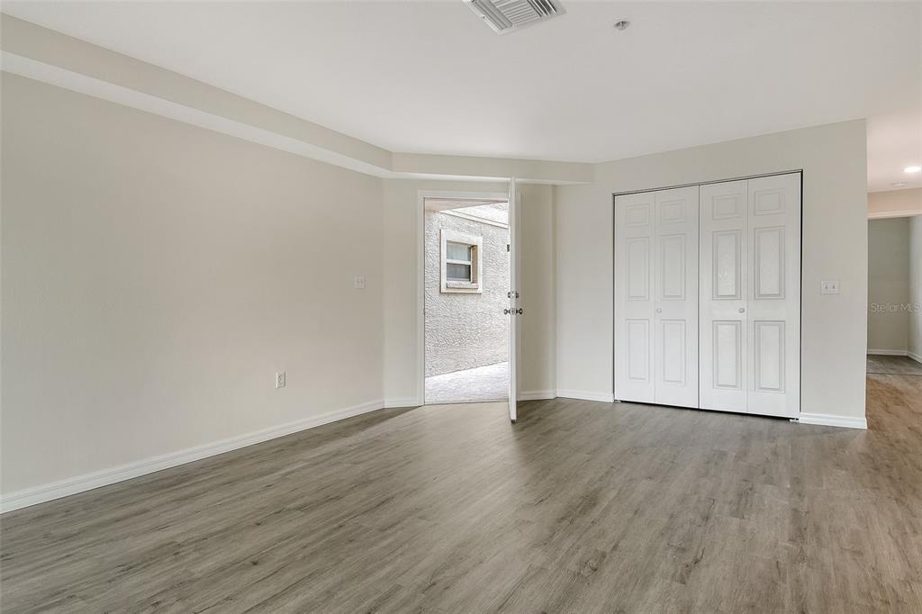 An empty room with light walls, wood-look flooring, a white closet, and an open door — 383 BOBBY JONES ROAD UNIT 383, SARASOTA, FL