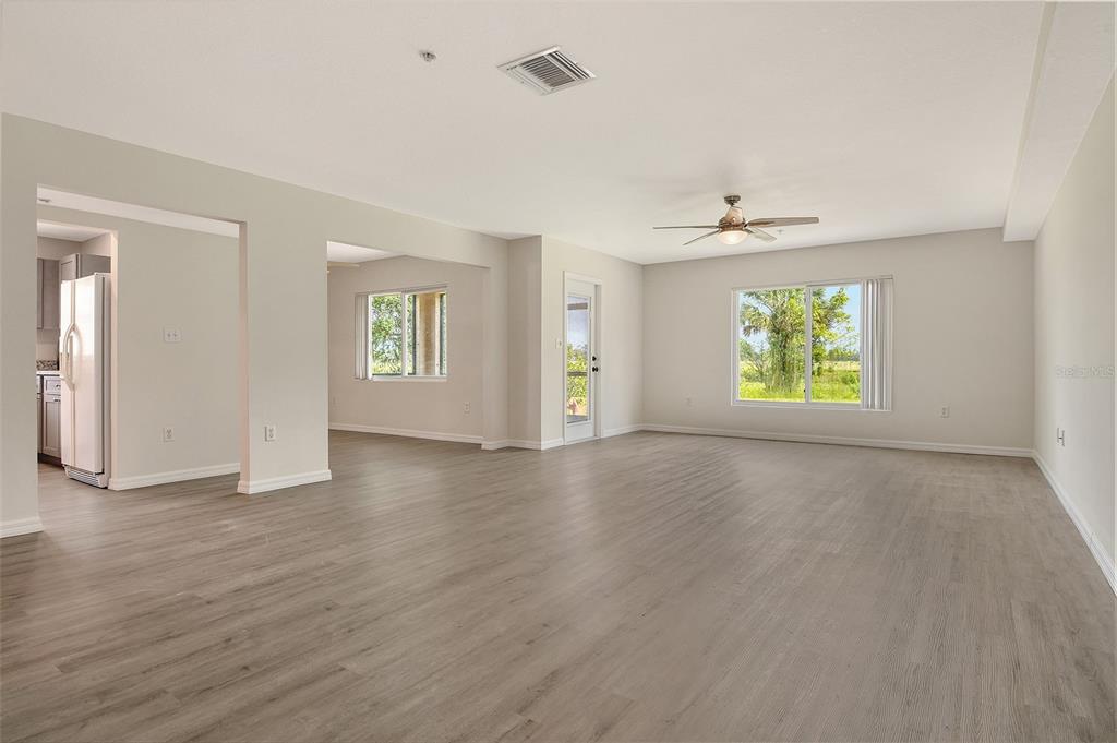 An open-concept living area features light gray wood-look flooring, neutral walls, and a ceiling fan — 383 BOBBY JONES ROAD UNIT 383, SARASOTA, FL