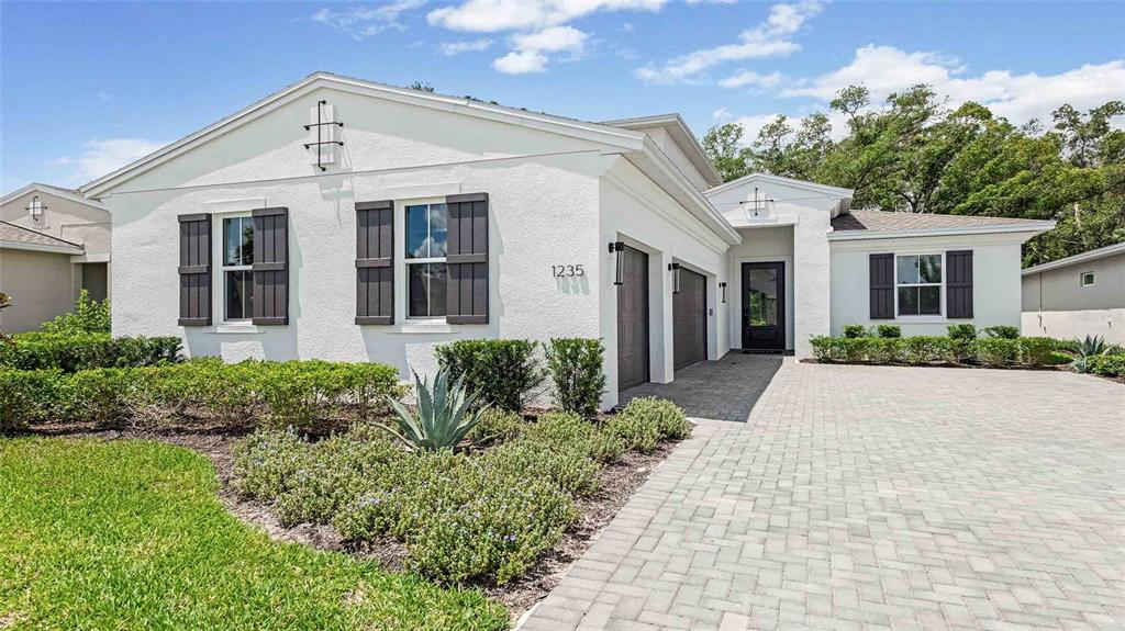 A white stucco house with dark shutters, a paved driveway, and a front-facing garage — 1235 CRESSWIND BOULEVARD, DELAND, FL