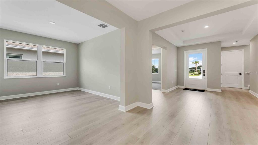 An interior view of a home featuring light wood flooring, gray walls, and an entryway — 1235 CRESSWIND BOULEVARD, DELAND, FL