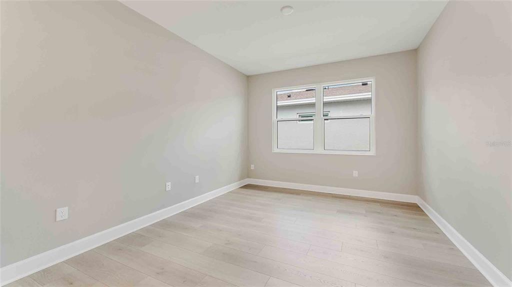 An empty bedroom features light-colored walls, wood-look flooring, and a window with white trim — 1235 CRESSWIND BOULEVARD, DELAND, FL