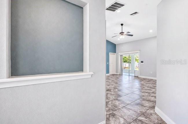 A view from a hallway looking into a living area with tile floors and sliding doors — 3975 SUNNYWOOD CIRCLE, LAKELAND, FL