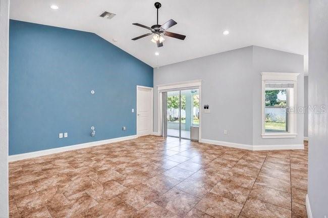 A living room features a blue accent wall, tile flooring, a ceiling fan, and sliding doors — 3975 SUNNYWOOD CIRCLE, LAKELAND, FL