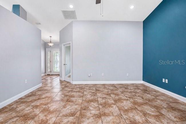 An empty room features light gray walls, a teal accent wall, and brown tiled flooring — 3975 SUNNYWOOD CIRCLE, LAKELAND, FL