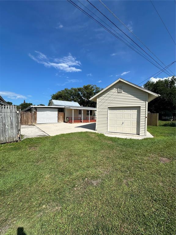 A detached garage stands in front of a house with a covered porch and driveway — 606 NEW YORK AVE UNIT New York Ave, ST CLOUD, FL