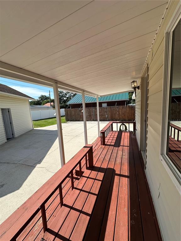 A covered wooden deck with a railing overlooks a concrete driveway and a neighboring house — 606 NEW YORK AVE UNIT New York Ave, ST CLOUD, FL