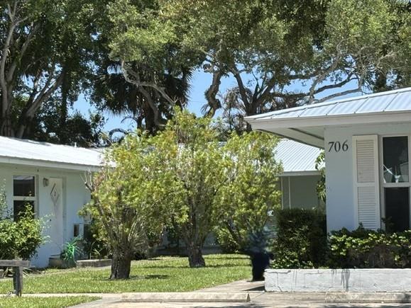 Exterior view of two white single-story buildings with metal roofs and surrounding trees — VERO BEACH, FL