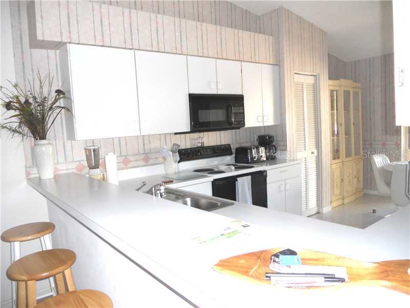 A kitchen with white cabinets, a breakfast bar, and striped wallpaper above the counters — 8911 VERANDA WAY UNIT 222, SARASOTA, FL