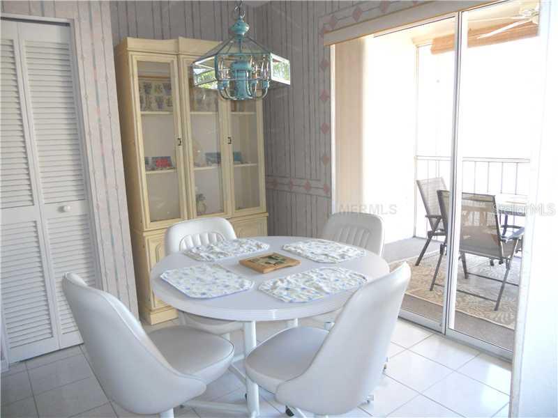 A dining area with a round white table, four chairs, a hutch, and a sliding door — 8911 VERANDA WAY UNIT 222, SARASOTA, FL