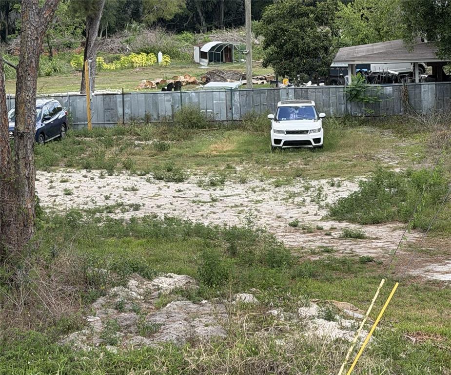 A vacant, sandy lot features a white SUV parked near a metal fence — 6806 NEW YORK DRIVE Lot C, TAMPA, FL