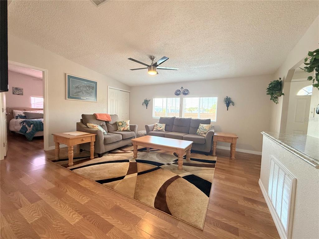 A living room features wood-look flooring, a patterned area rug, and two gray sofas — 8438 FORMEL AVENUE, PORT RICHEY, FL