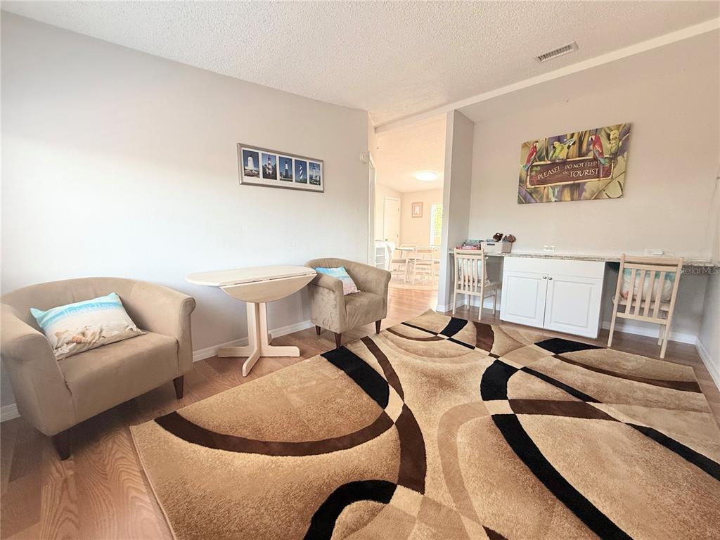 A living area features a patterned rug, two armchairs, a small table, and built-in desks — 8438 FORMEL AVENUE, PORT RICHEY, FL