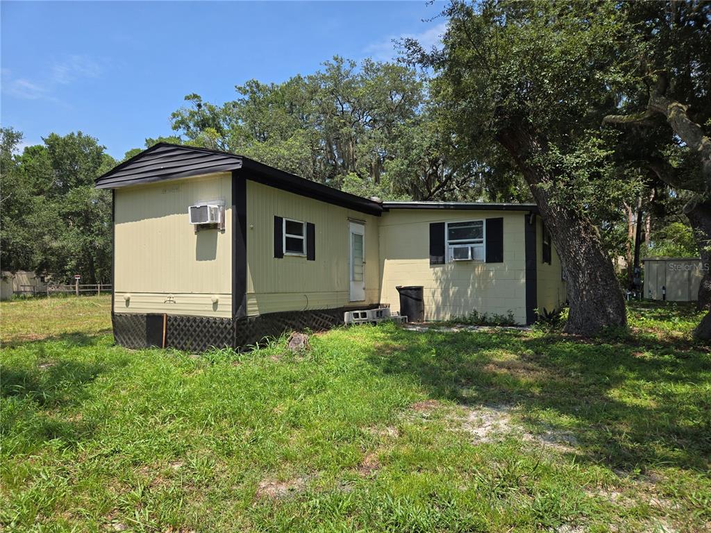 A single-story mobile home with light yellow siding and black trim sits on a grassy lot — 1665 BODKIN LANE, OVIEDO, FL