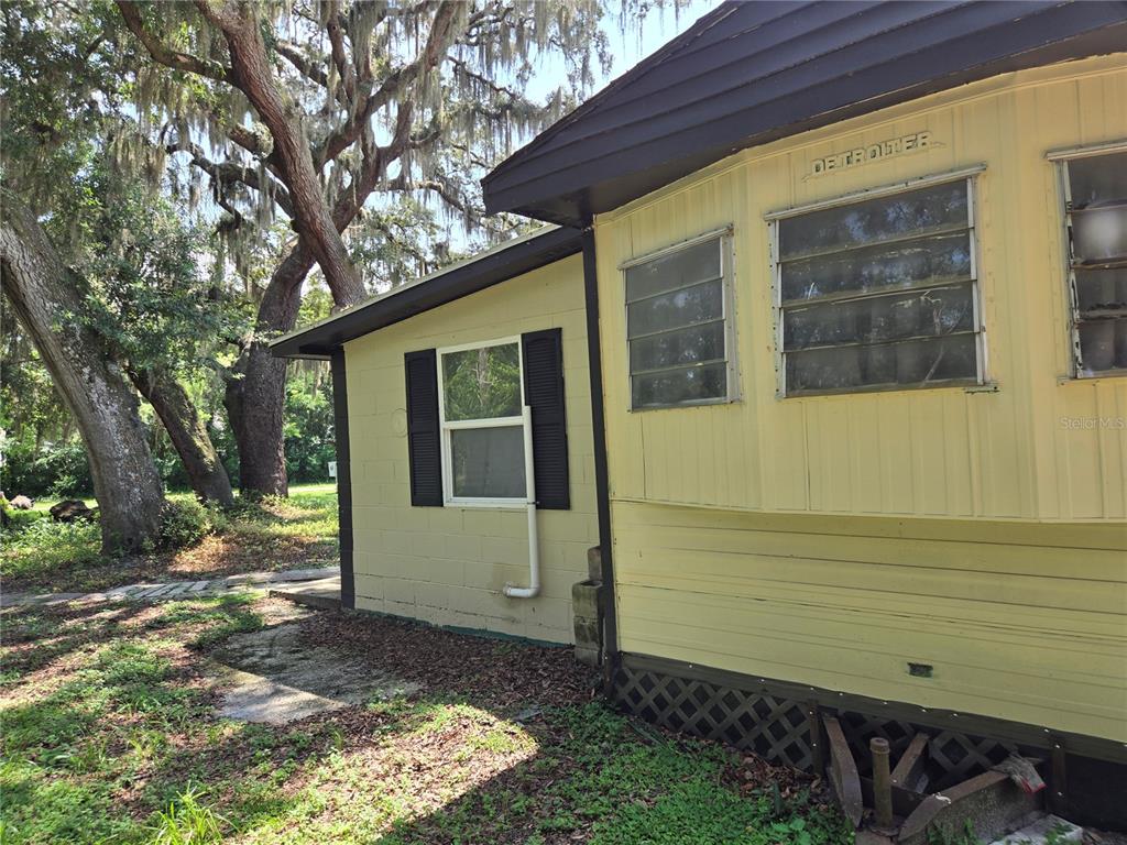 The exterior of a yellow mobile home features a block wall section and jalousie windows — 1665 BODKIN LANE, OVIEDO, FL