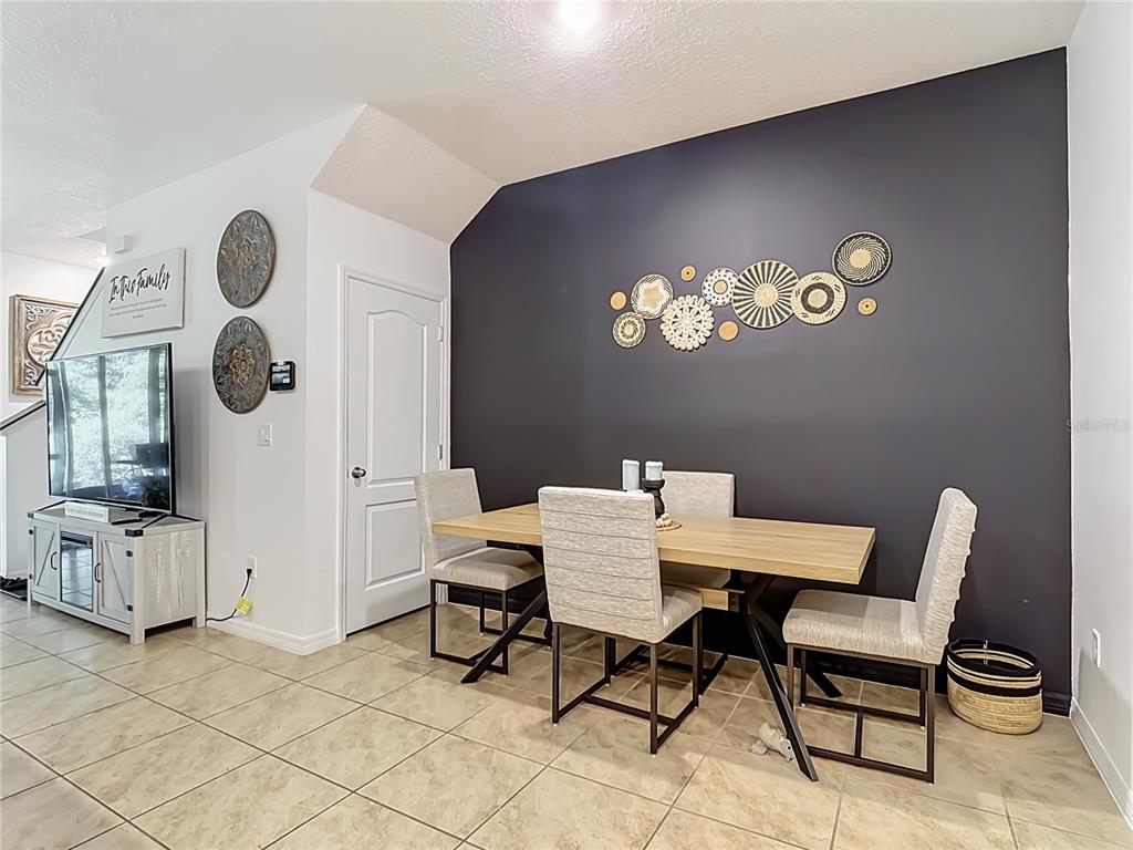 A dining area features a light wood table, four upholstered chairs, and a dark accent wall — 1229 YELLOW FINCH DRIVE, DAVENPORT, FL