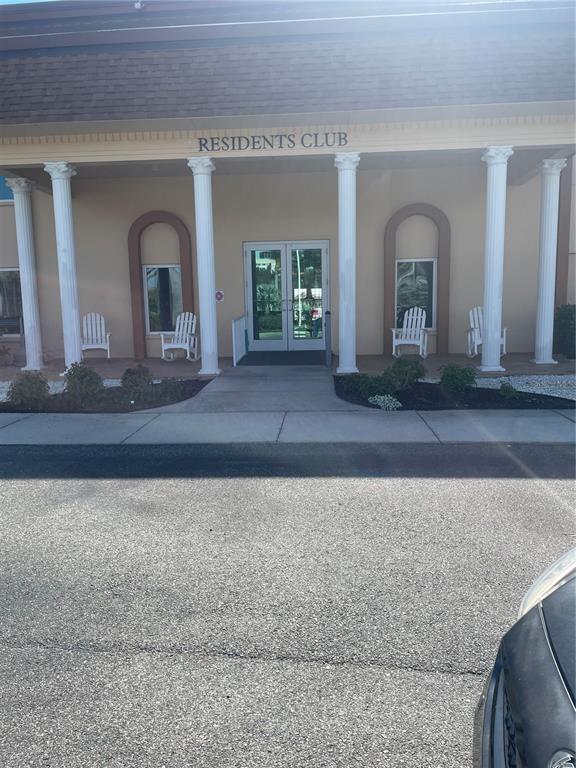 The exterior of a building labeled Residents Club features white columns and rocking chairs — 5200 BRITTANY DRIVE S UNIT 1804, ST PETERSBURG, FL