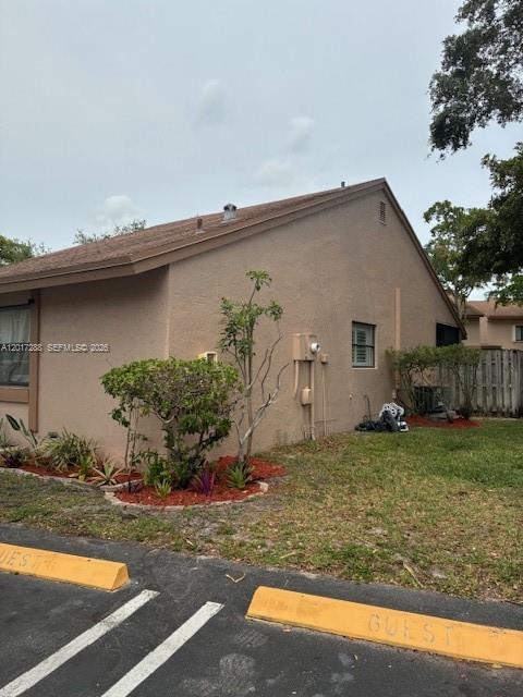 A side view of a tan stucco building with a brown shingled roof and landscaping — 19 Chestnut Cir, Cooper City FL 33026, COOPER CITY, FL