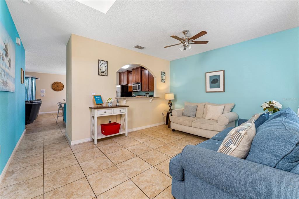 A living room with tile floors, a blue accent wall, and an arched kitchen pass-through — 1144 CYPRESS POINTE BOULEVARD, DAVENPORT, FL