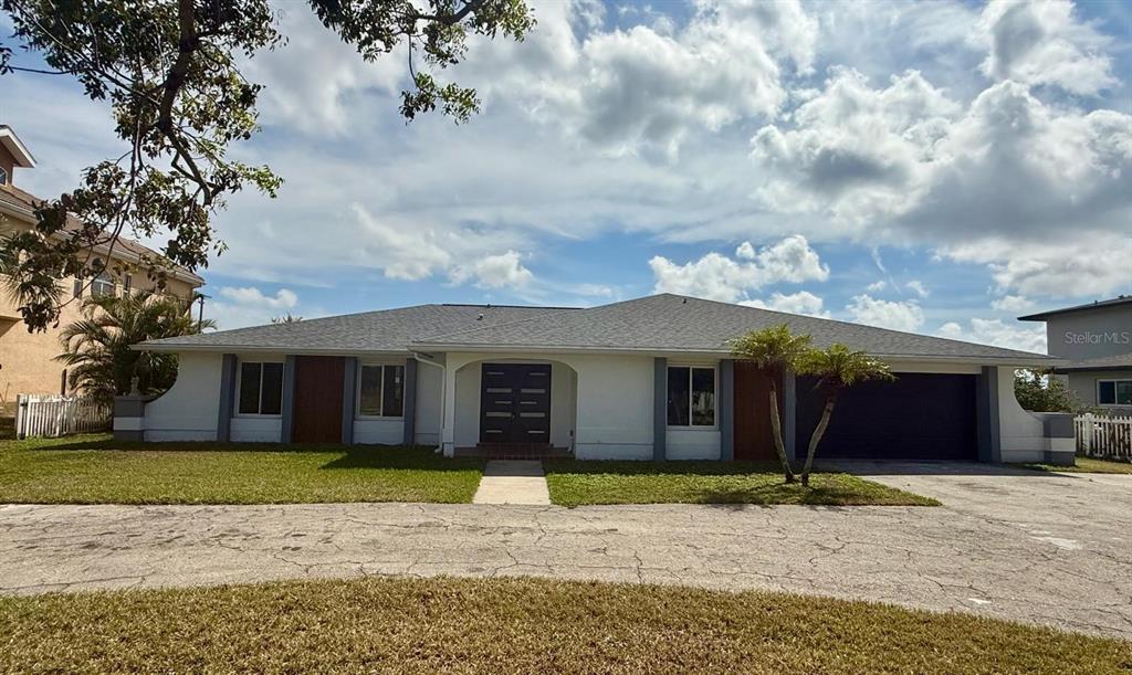 A single-story white house with a gray roof, dark double doors, and a paved driveway — 111 E NORTH SHORE AVENUE, NORTH FORT MYERS, FL