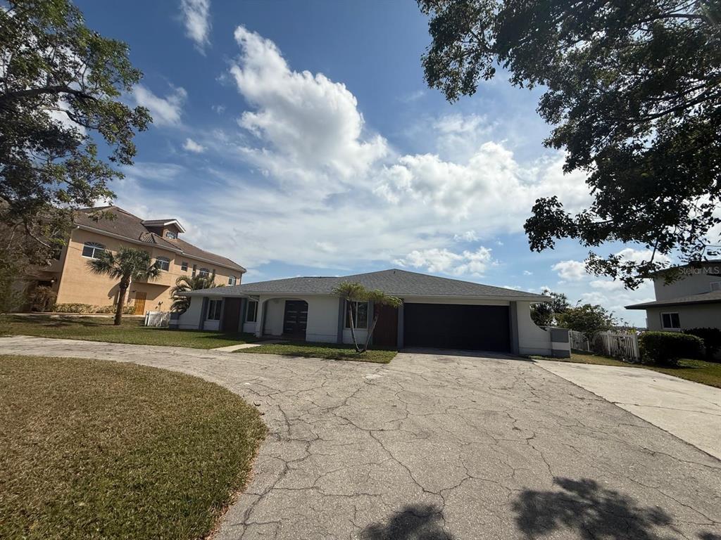 A single-story house with a dark garage door and a cracked concrete driveway — 111 E NORTH SHORE AVENUE, NORTH FORT MYERS, FL