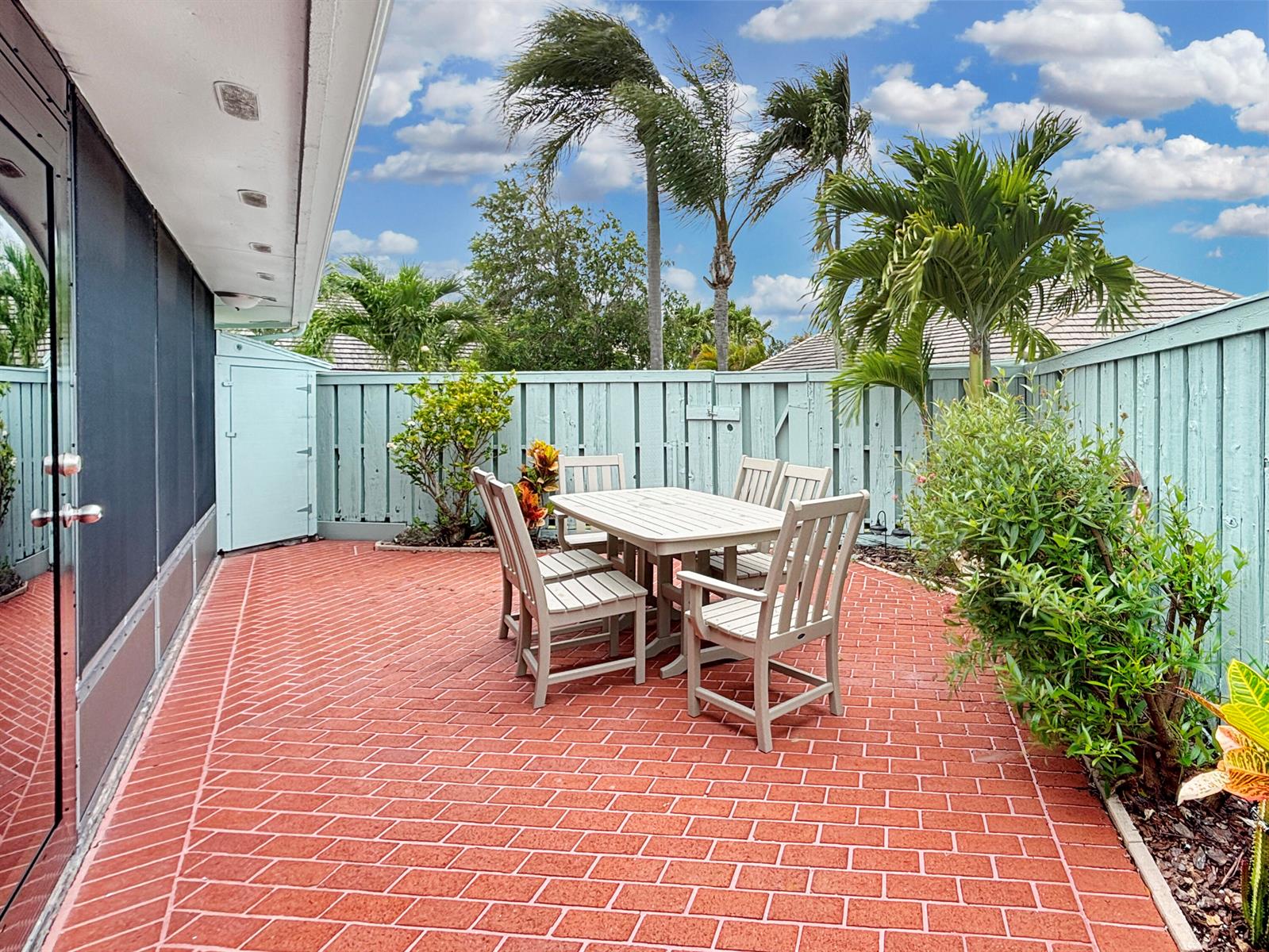 A patio with red brick pavers, a dining set, and a light blue wooden fence — 1127 E Seminole Avenue # 8a, Jupiter FL 33477, JUPITER, FL