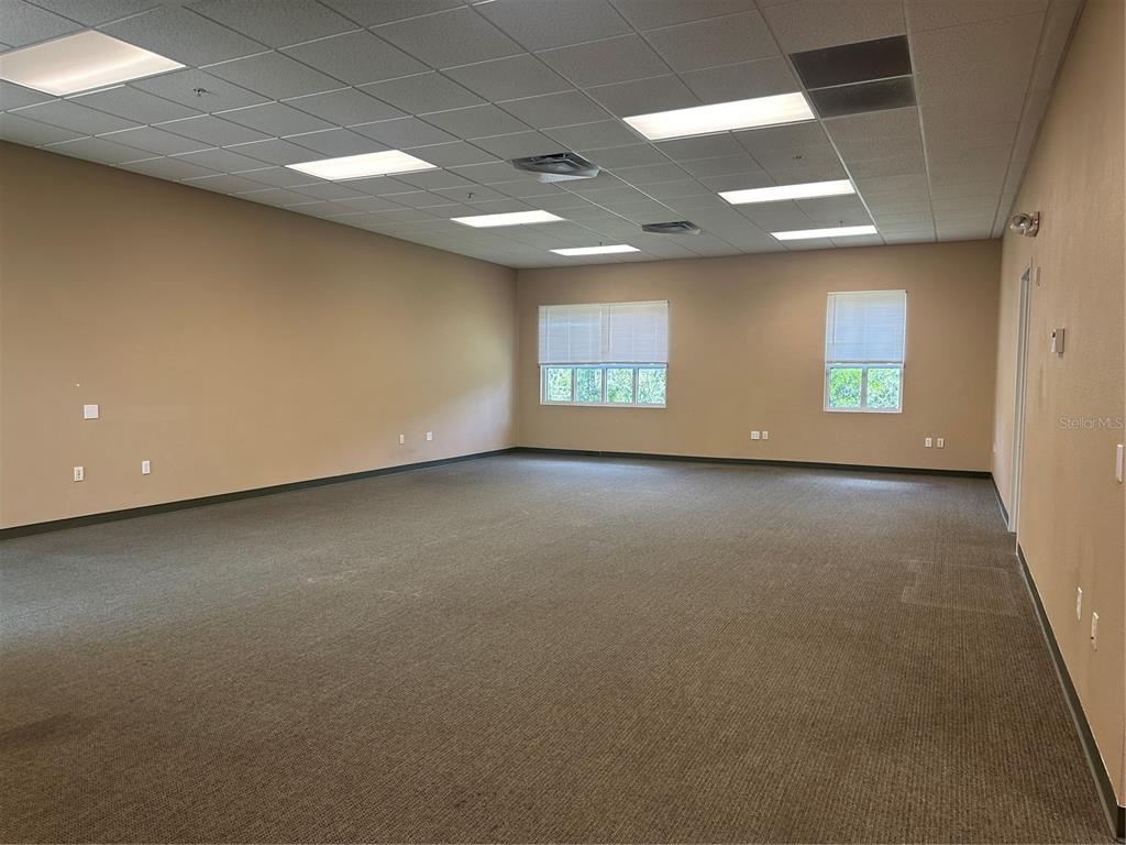 An empty office room features beige walls, gray carpeting, and a drop ceiling with lights — 1611 12TH STREET E UNIT B, PALMETTO, FL
