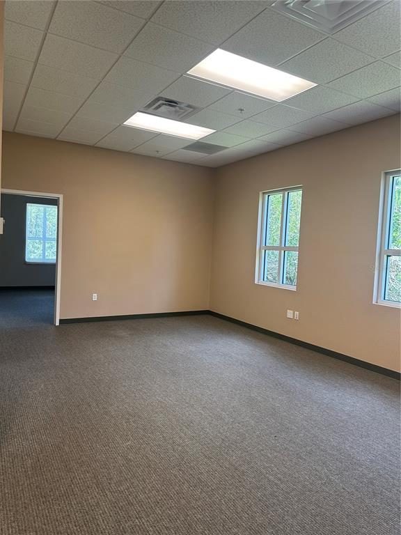 An empty office with beige walls, gray carpet, and two rectangular ceiling light fixtures — 1611 12TH STREET E UNIT B, PALMETTO, FL