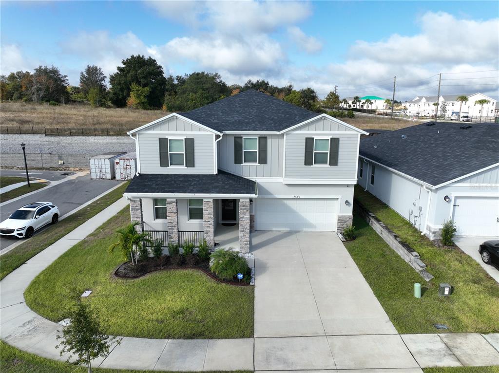 An aerial view of a two-story suburban house with gray siding and a stone facade — 9660 WESTSIDE HILLS DRIVE, DAVENPORT, FL