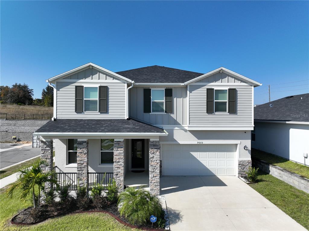 A two-story house with light gray siding, stone accents, and a two-car garage — 9660 WESTSIDE HILLS DRIVE, DAVENPORT, FL