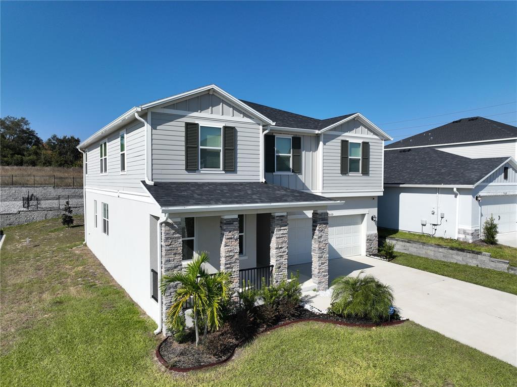 A two-story house with light gray siding, stone-accented columns, and a two-car garage — 9660 WESTSIDE HILLS DRIVE, DAVENPORT, FL