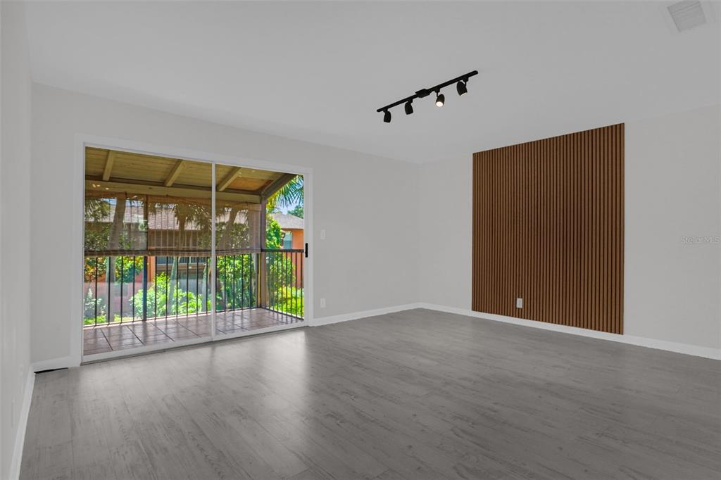 A room with gray wood-look flooring, a wood slat accent wall, and a sliding glass door — 754 E MICHIGAN STREET UNIT 174, ORLANDO, FL