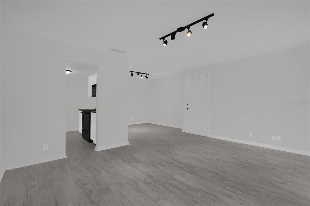 An open-concept living area features light gray wood-look flooring and black track lighting — 754 E MICHIGAN STREET UNIT 174, ORLANDO, FL