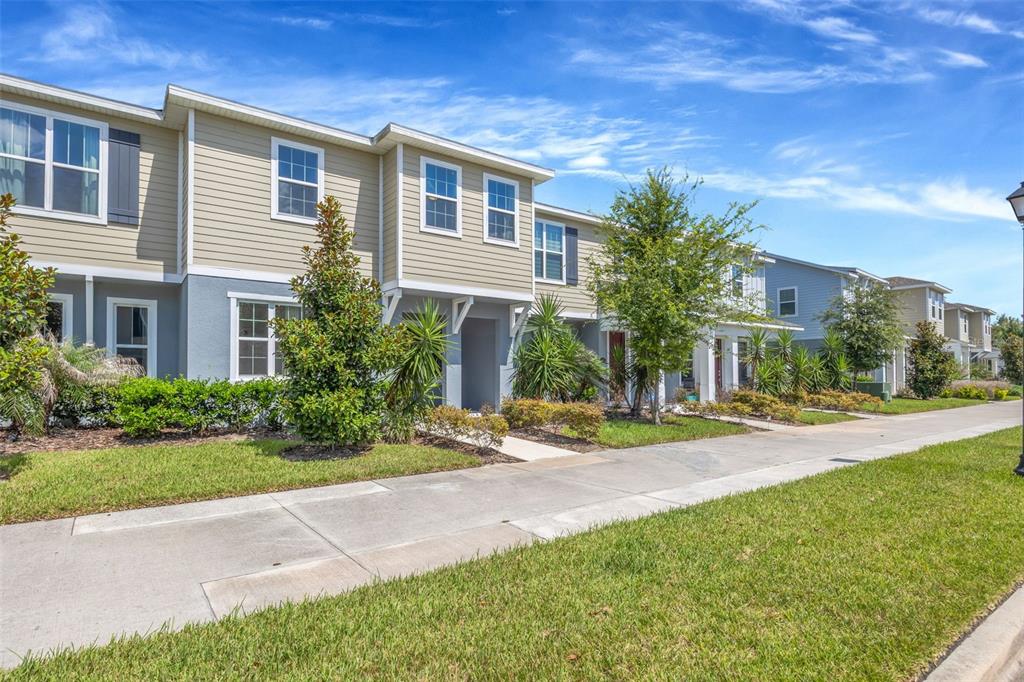 A row of two-story townhouses with beige siding and gray stucco lower levels — 5022 AVALON PARK BOULEVARD, WESLEY CHAPEL, FL