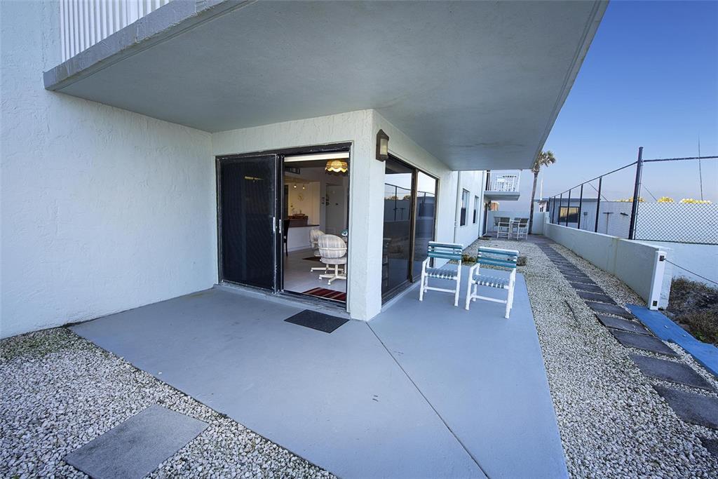 A covered concrete patio features sliding glass doors leading into a residential interior space — 1571 S ATLANTIC AVENUE UNIT 111, NEW SMYRNA BEACH, FL
